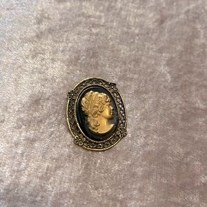 Vintage cameo brooch. Black background, aged gold color foreground.